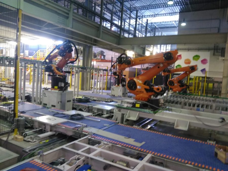 Roboty przemysłowe przy linii przenośników rolkowych w hali produkcyjnej