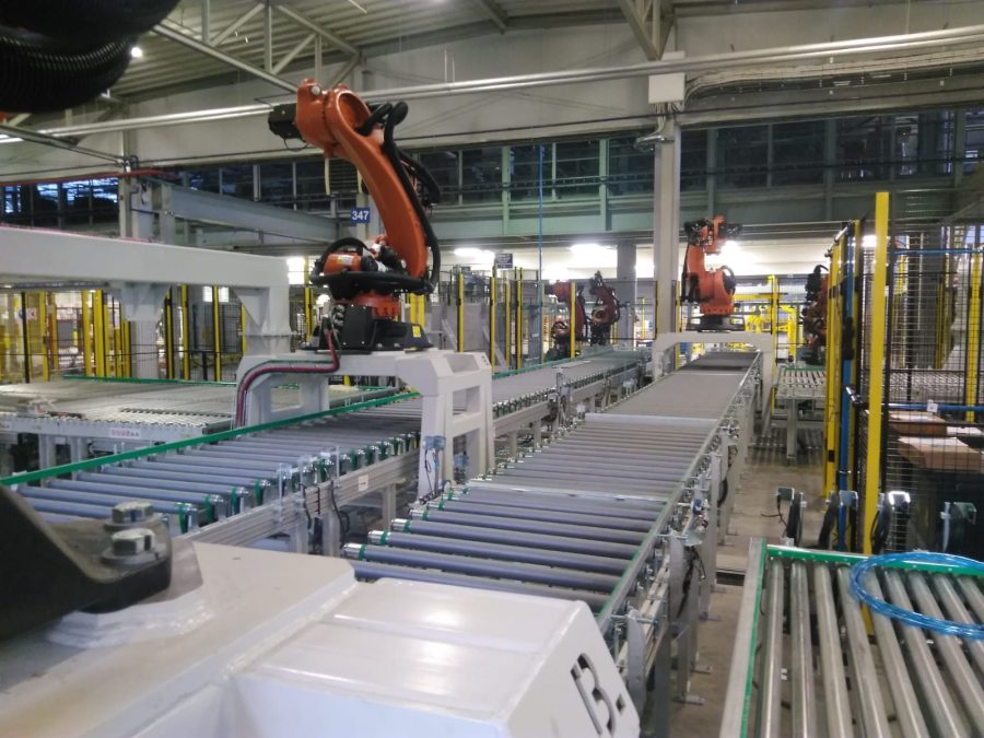 Linia przenośników rolkowych z robotem przemysłowym w hali