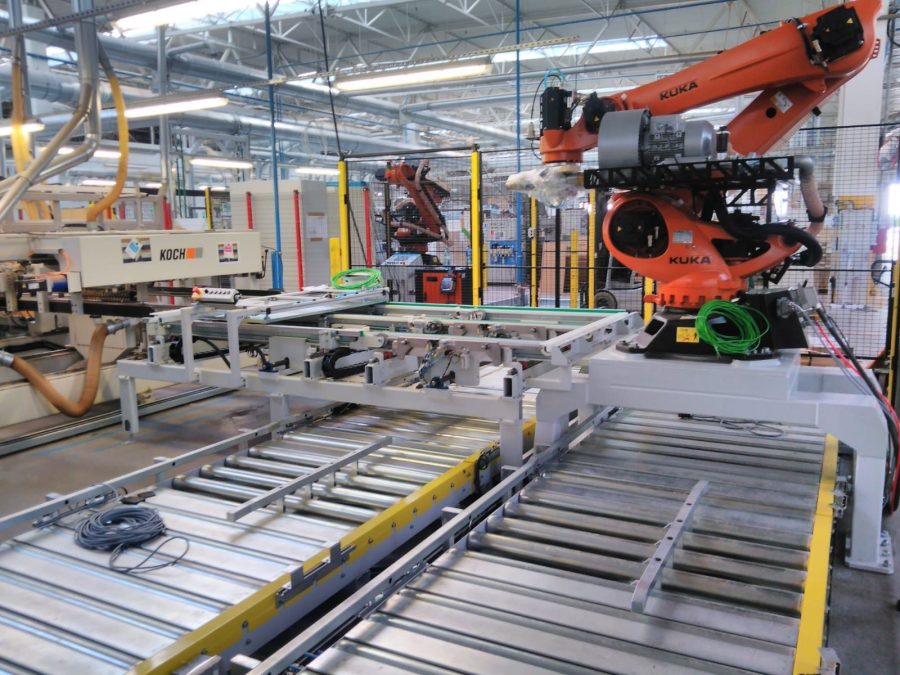 Robot przemysłowy nad przenośnikiem rolkowym na stanowisku produkcyjnym