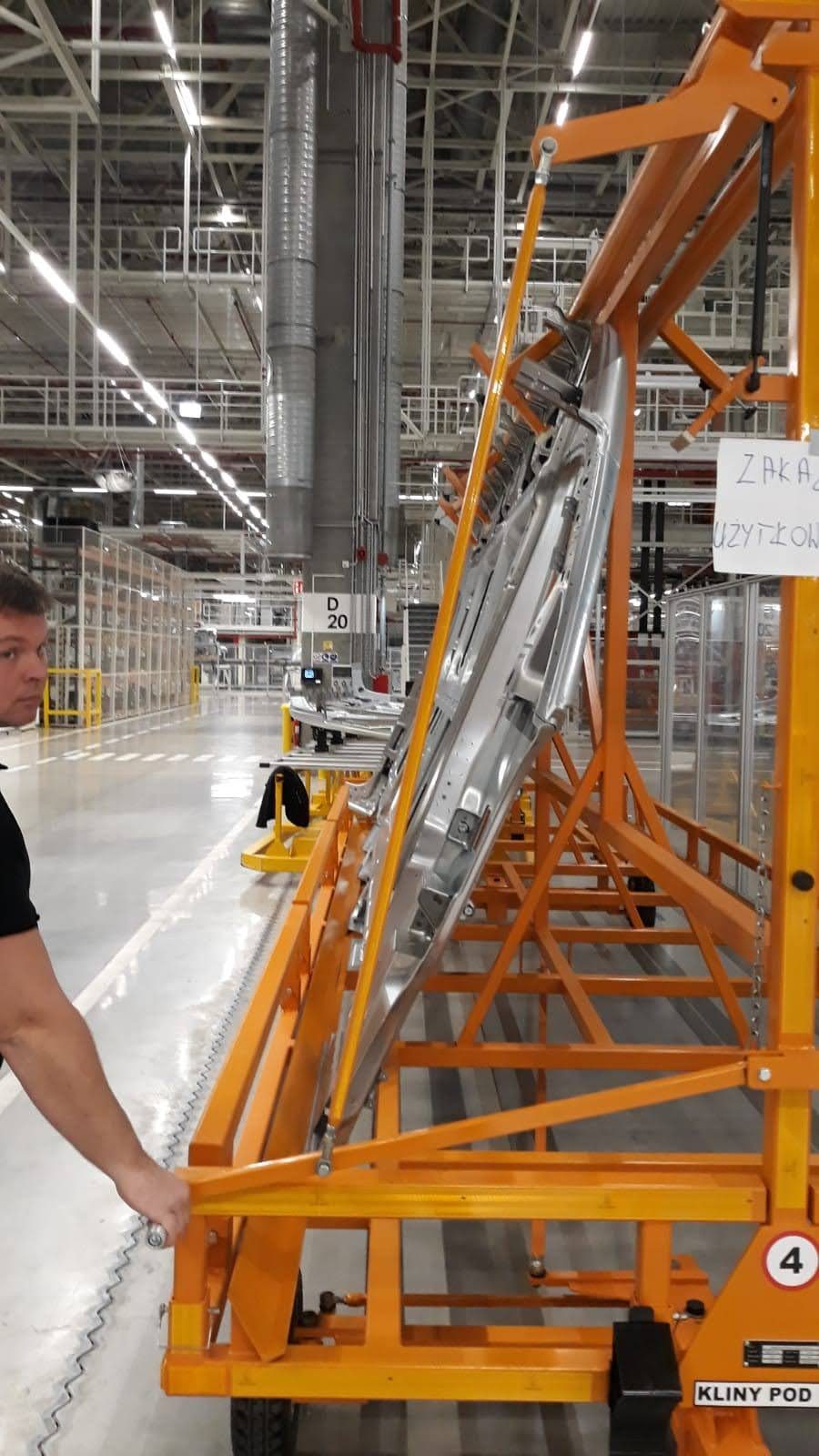 Pomarańczowy wózek transportowy na detale w hali produkcyjnej