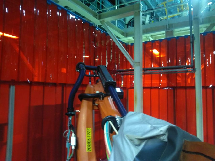 Robot spawalniczy wewnątrz zabudowy z czerwoną kurtyną