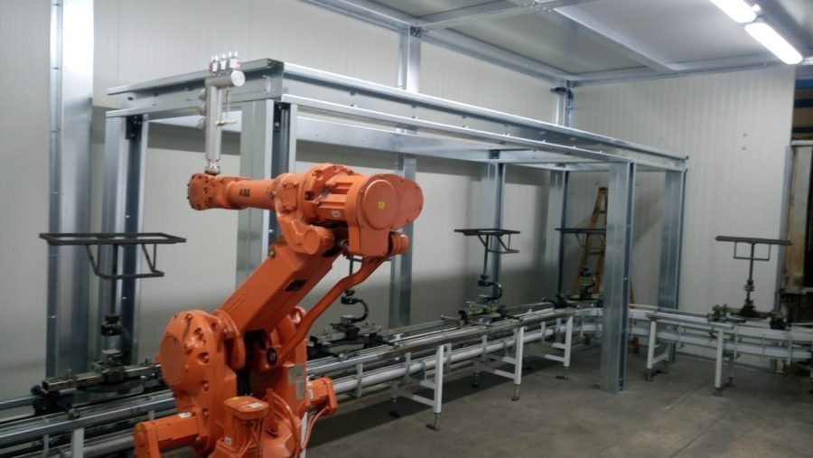 Robot przemysłowy przy stalowej ramie z przenośnikiem rolkowym